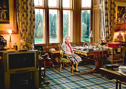 The Queen at her desk at Balmoral. In front of her is a touching photograph of her as a young girl with her father, while behind her is a cuddly toy corgi and a Bakelite telephone which has no numbers as it connects directly to the switchboard