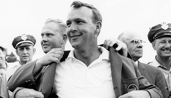 Lifelong close friend and rival Jack Nicklaus puts the famous "green jacket" on Arnie after the King wins the 1964 Master's golf championship.